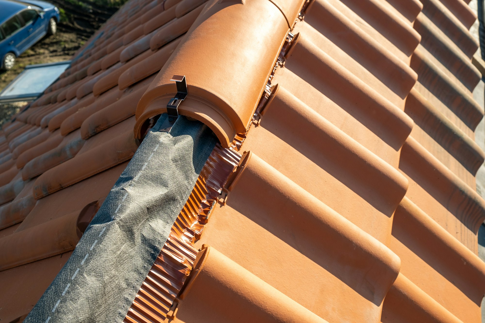 Closeup of yellow ceramic roofing ridge tiles on top of residential building roof under construction