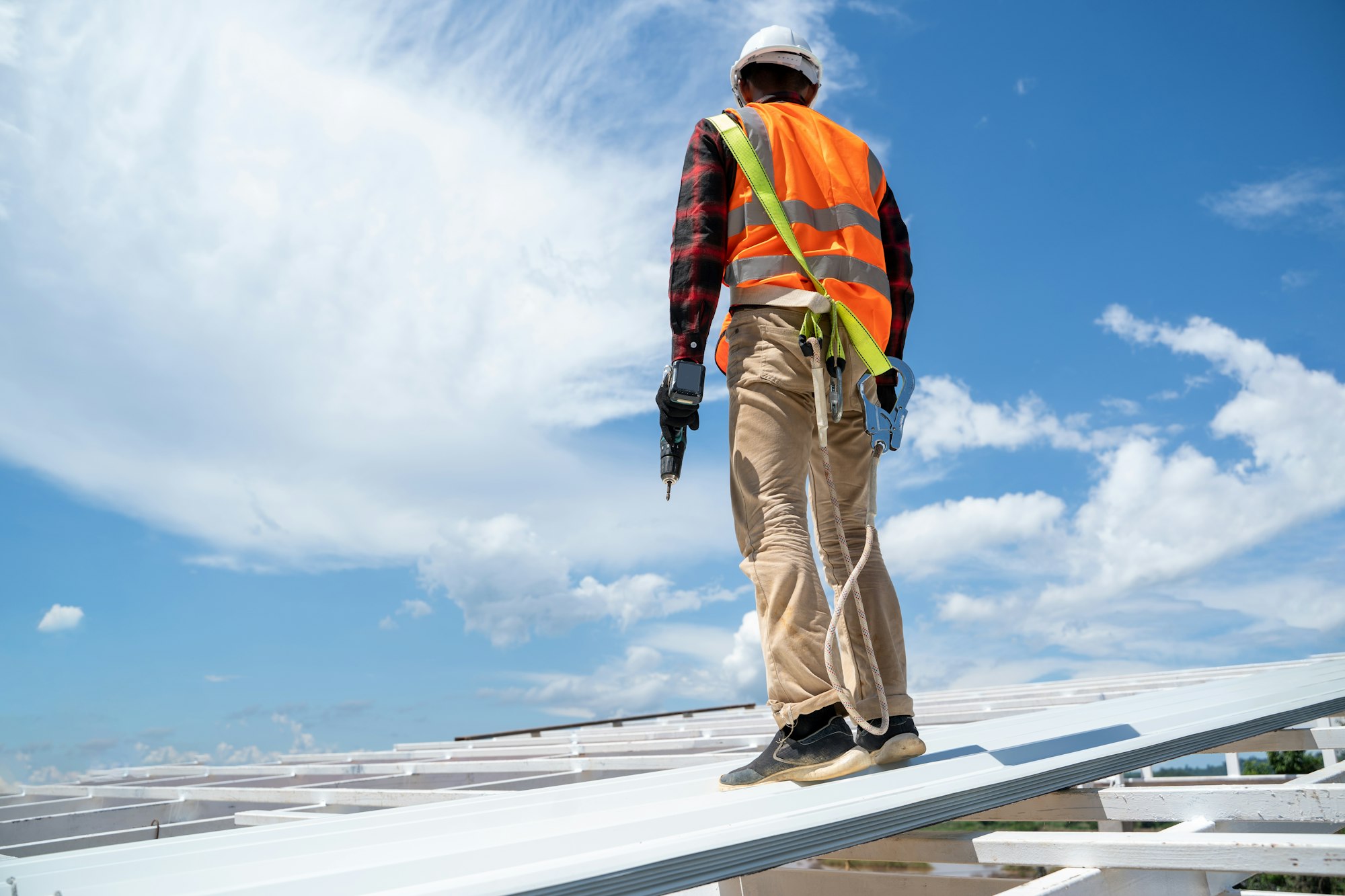 Roofer working at metal profile roof installation,Roofing tools,Electric drill used on new roofs.