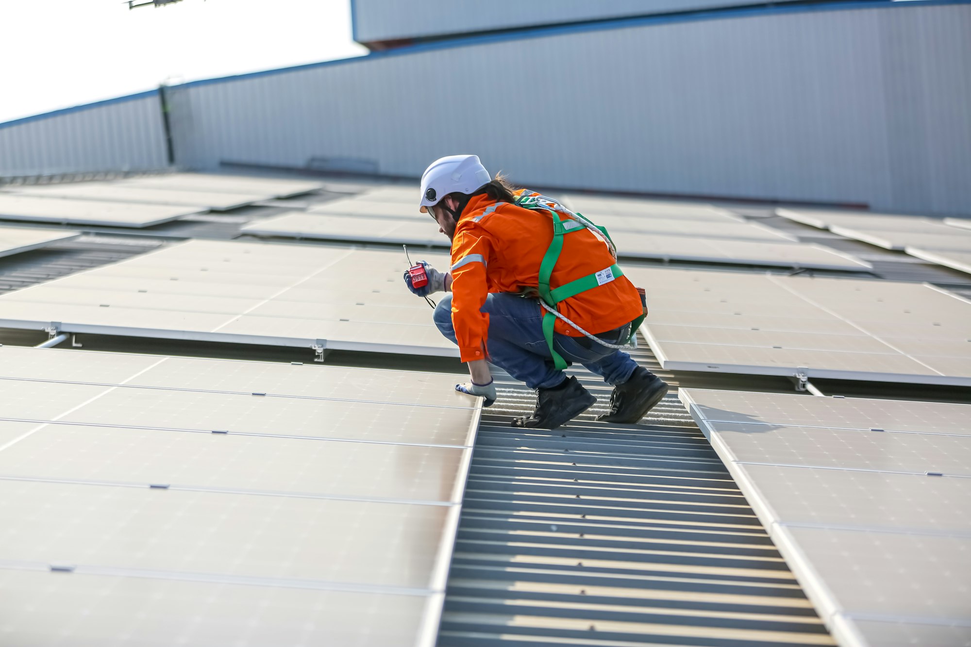 Workers Installing Solar Panels on warehouse Roof.